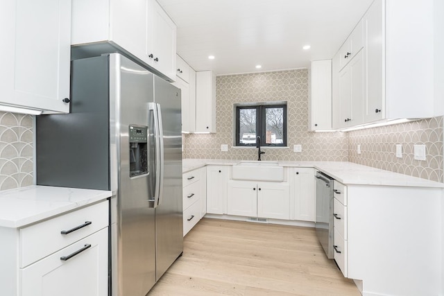 kitchen featuring white cabinets, light stone counters, appliances with stainless steel finishes, and sink