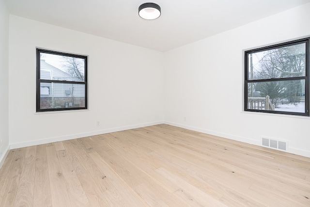 empty room featuring light wood-type flooring and a healthy amount of sunlight