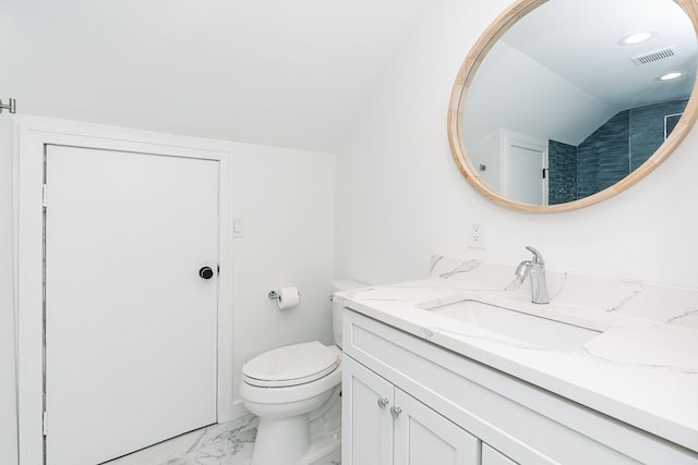 bathroom with toilet, vanity, and lofted ceiling