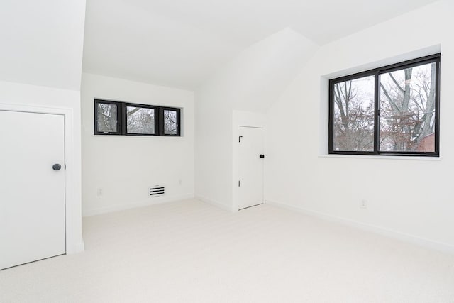 interior space featuring light colored carpet and lofted ceiling