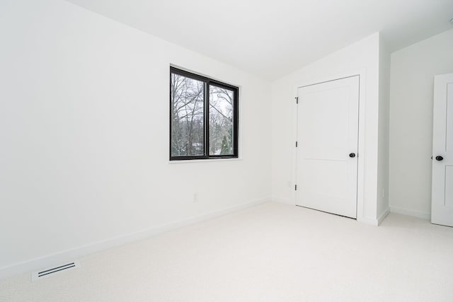 carpeted spare room featuring vaulted ceiling