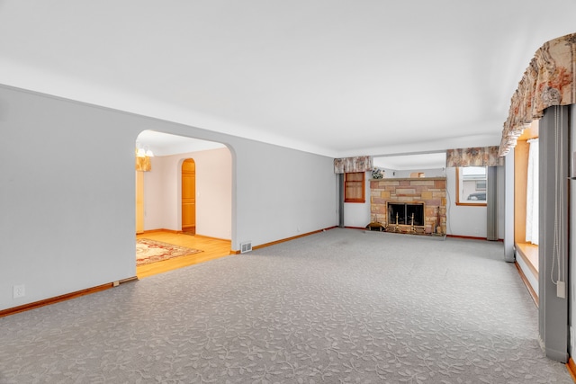 unfurnished living room featuring carpet floors and a stone fireplace