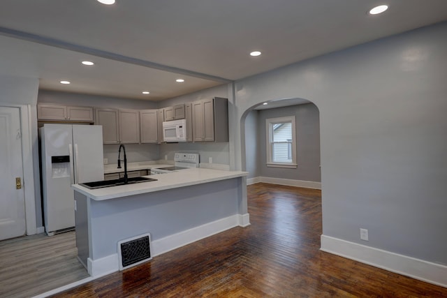 kitchen featuring sink, gray cabinetry, dark hardwood / wood-style floors, and white appliances