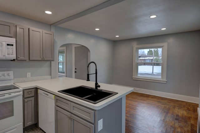 kitchen with gray cabinets, sink, kitchen peninsula, and white appliances