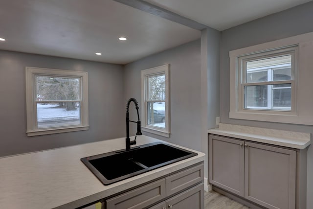 kitchen with light wood-type flooring, a wealth of natural light, gray cabinetry, and sink