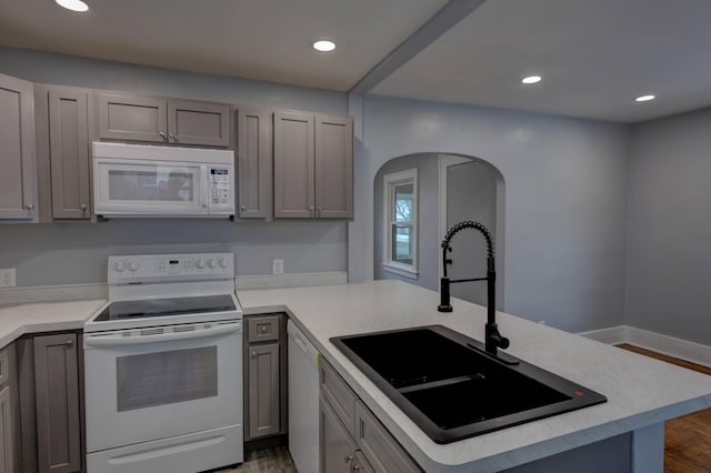 kitchen with sink, white appliances, gray cabinets, and kitchen peninsula