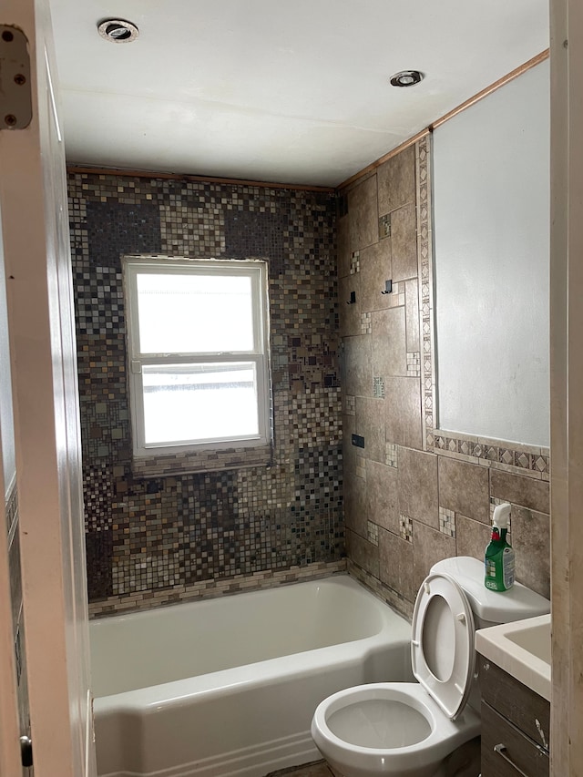 full bathroom featuring toilet, tile walls, tiled shower / bath, and vanity