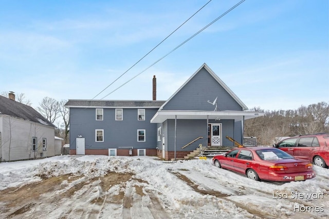 snow covered property with covered porch