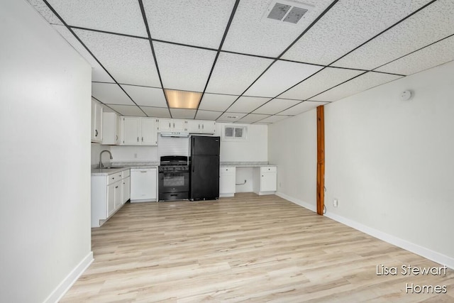 kitchen with sink, light hardwood / wood-style flooring, white cabinets, and black appliances