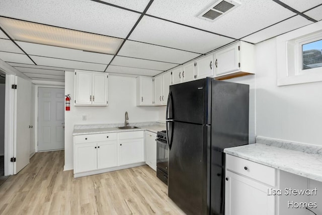 kitchen with white cabinetry, sink, a drop ceiling, and black appliances