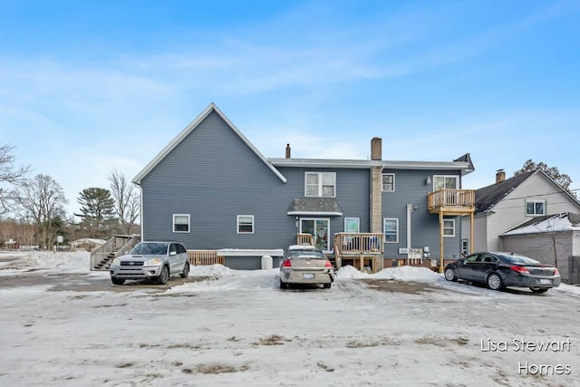 snow covered rear of property featuring a deck