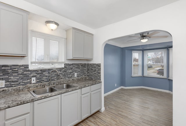 kitchen featuring ceiling fan, sink, tasteful backsplash, and light hardwood / wood-style flooring