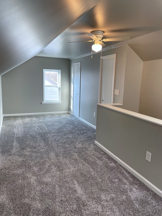 additional living space featuring dark carpet and vaulted ceiling