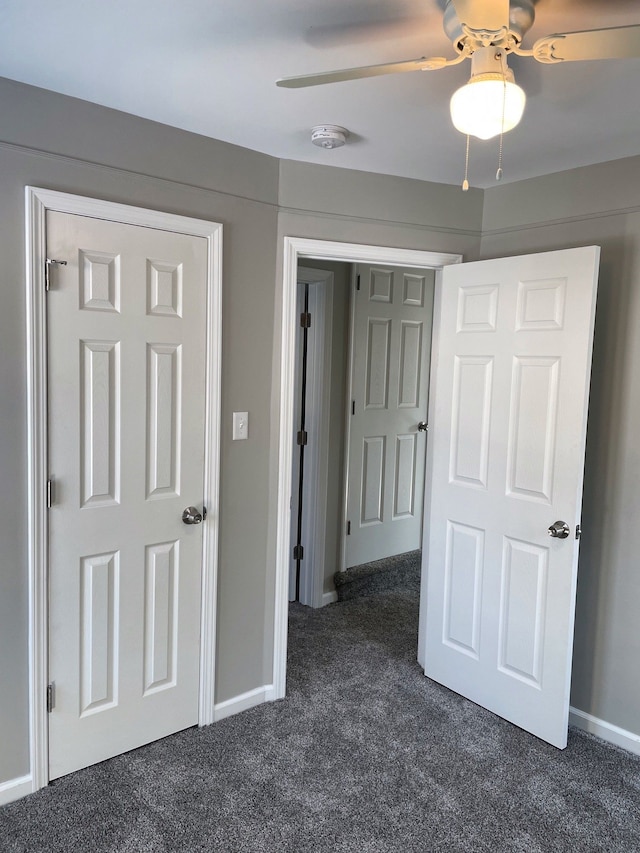 unfurnished bedroom with ceiling fan and dark colored carpet