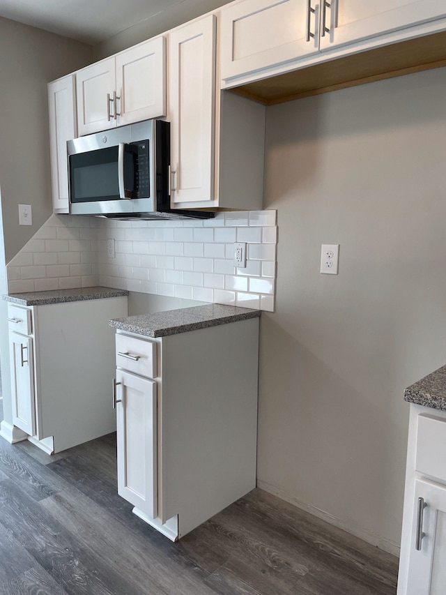 kitchen featuring white cabinets, decorative backsplash, dark hardwood / wood-style floors, and dark stone counters