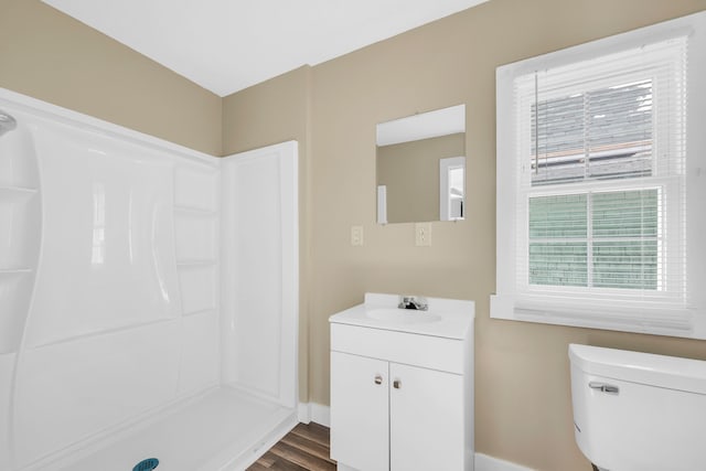 bathroom featuring toilet, vanity, wood-type flooring, and a shower