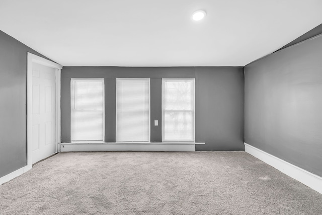 carpeted empty room with vaulted ceiling and a wealth of natural light