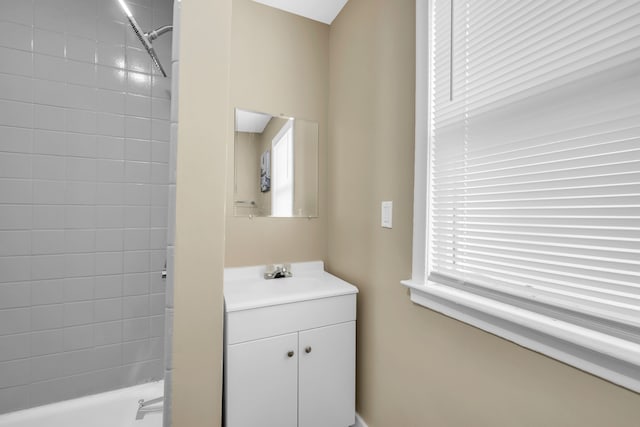 bathroom with tiled shower / bath combo, vanity, and a healthy amount of sunlight