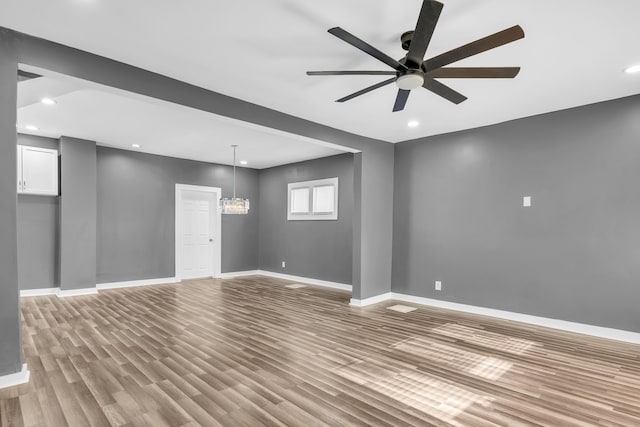 interior space featuring ceiling fan with notable chandelier and light hardwood / wood-style floors