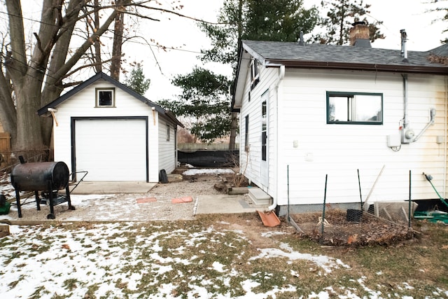 snow covered property featuring an outbuilding and a garage