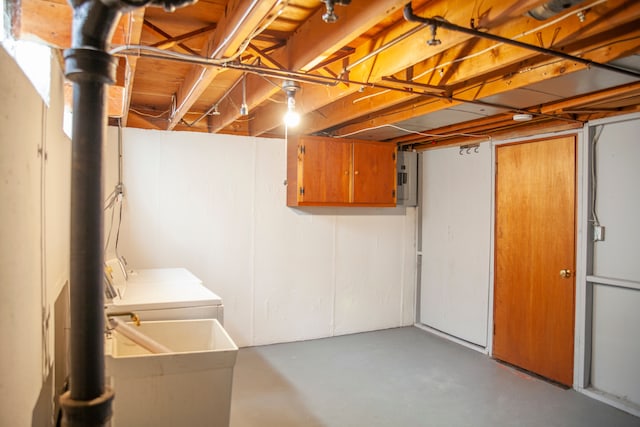 basement featuring washing machine and dryer, electric panel, and sink