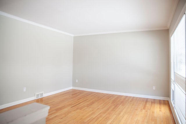 empty room with hardwood / wood-style floors and crown molding