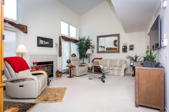 carpeted living room with a wealth of natural light, a high ceiling, and a tile fireplace