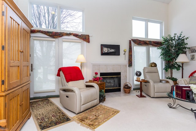 carpeted living room with a towering ceiling and a tiled fireplace