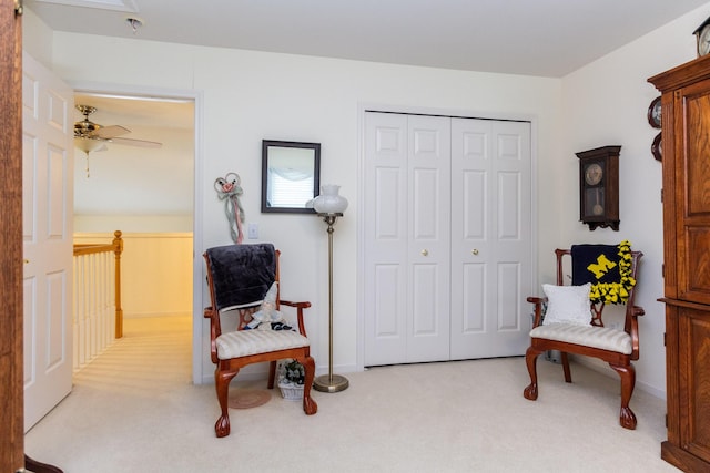 sitting room with ceiling fan and light colored carpet