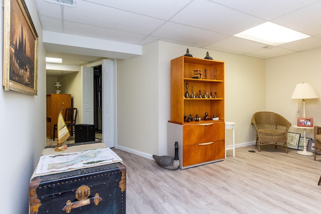 living area with light hardwood / wood-style flooring and a drop ceiling