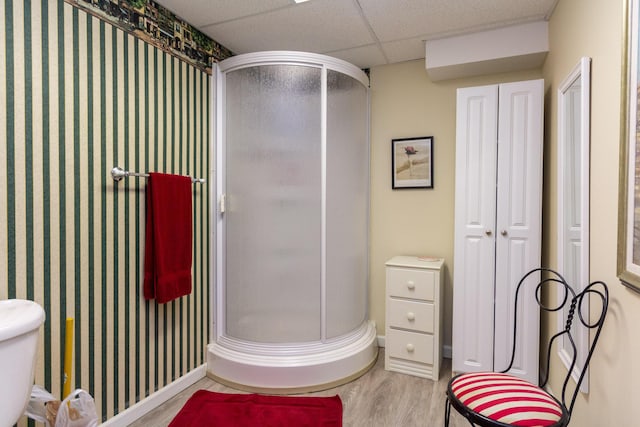 bathroom featuring a shower with shower door, a paneled ceiling, and wood-type flooring