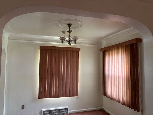 unfurnished room featuring a chandelier, arched walkways, and crown molding
