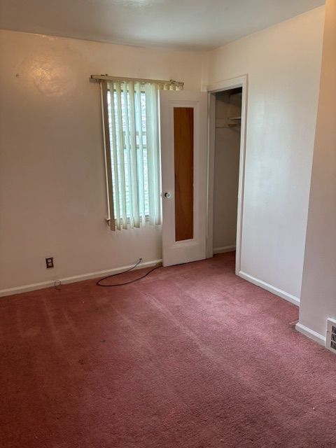 unfurnished bedroom with carpet floors, baseboards, and a closet