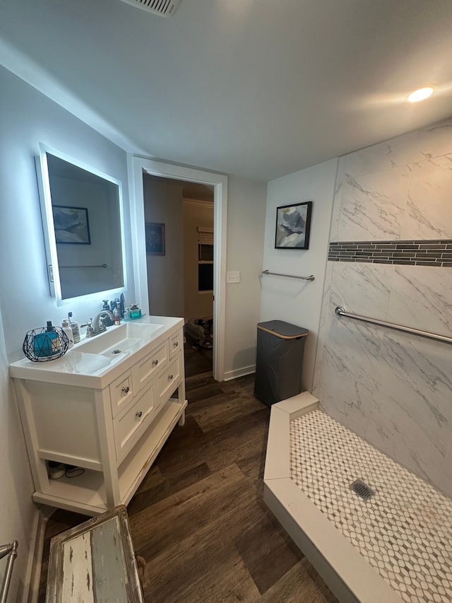 bathroom featuring a tile shower, vanity, and wood finished floors