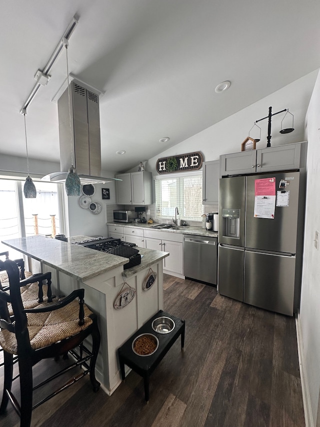 kitchen with a center island, a sink, appliances with stainless steel finishes, a kitchen bar, and dark wood-style flooring
