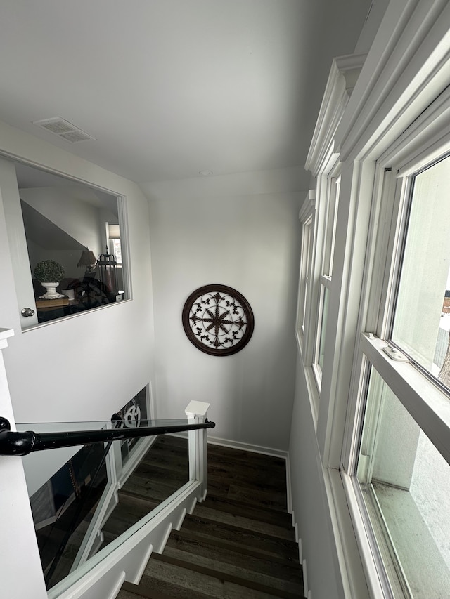stairway featuring wood finished floors, visible vents, and baseboards