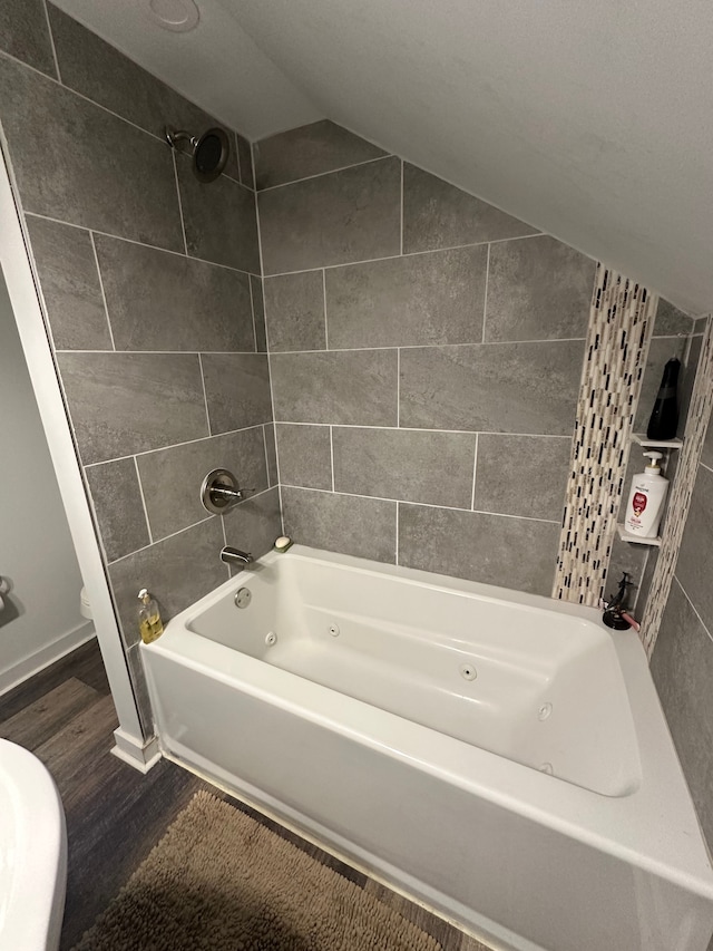 bathroom featuring lofted ceiling, wood-type flooring, and tiled shower / bath