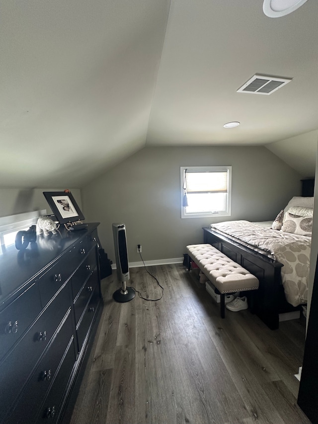 bedroom with vaulted ceiling, wood finished floors, visible vents, and baseboards