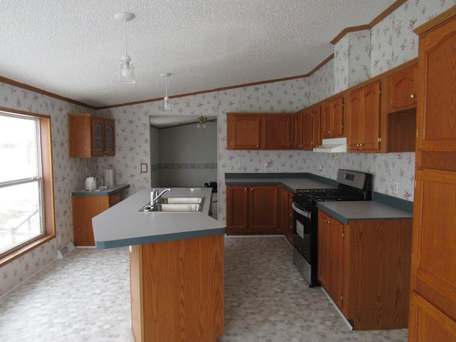 kitchen featuring gas stove, sink, ceiling fan, a center island with sink, and crown molding