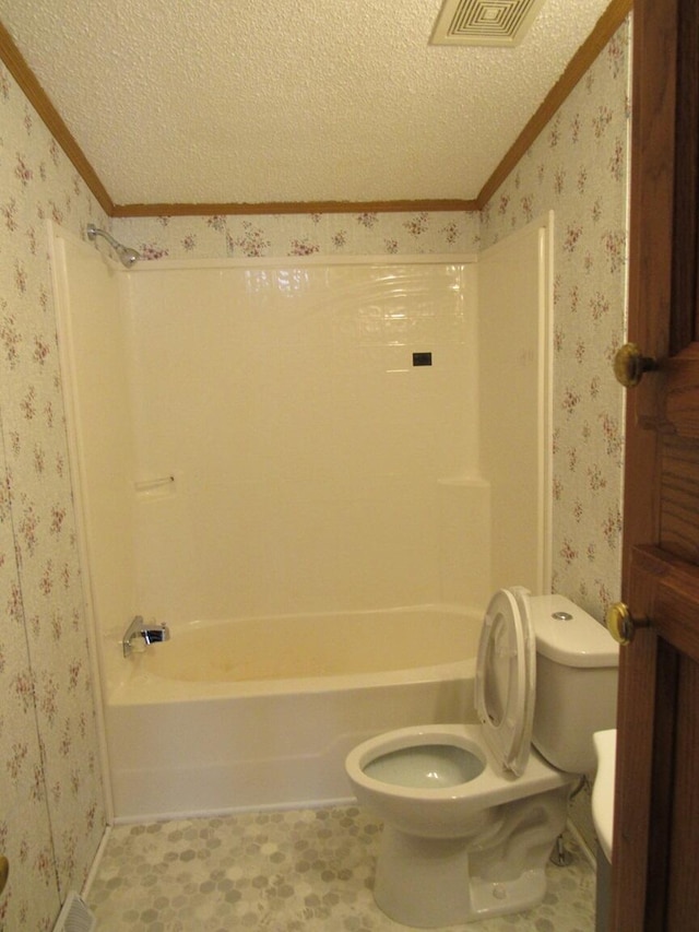 bathroom featuring toilet, shower / washtub combination, ornamental molding, and a textured ceiling