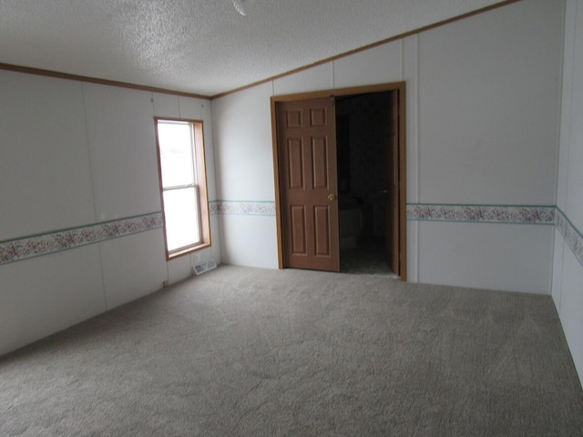 carpeted empty room featuring a textured ceiling