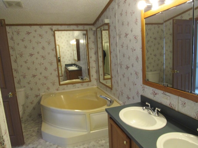 bathroom featuring a textured ceiling, crown molding, a bathtub, and vanity