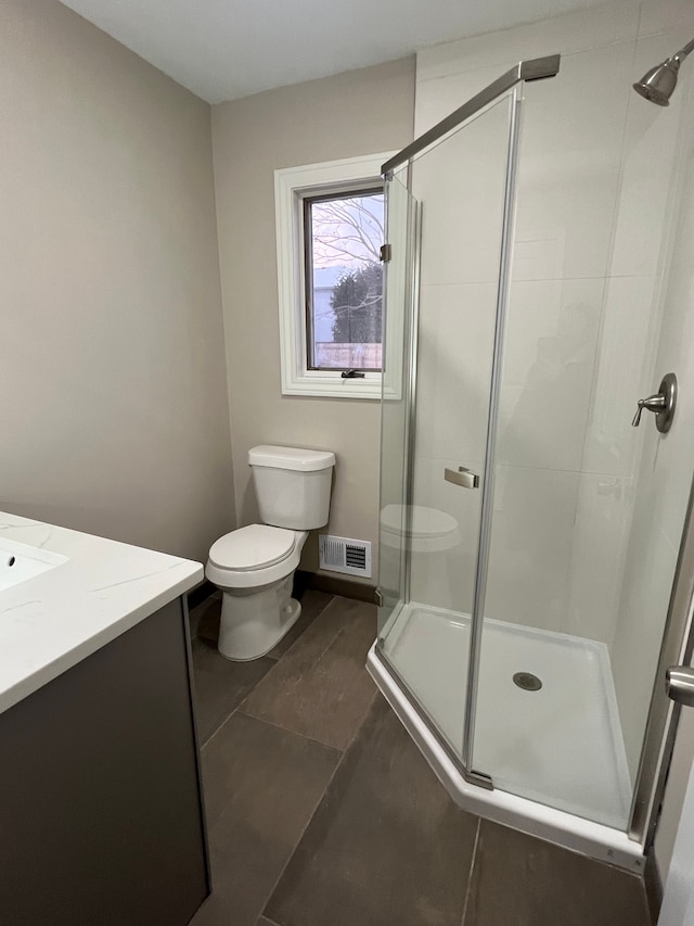 bathroom with toilet, a shower with door, and vanity