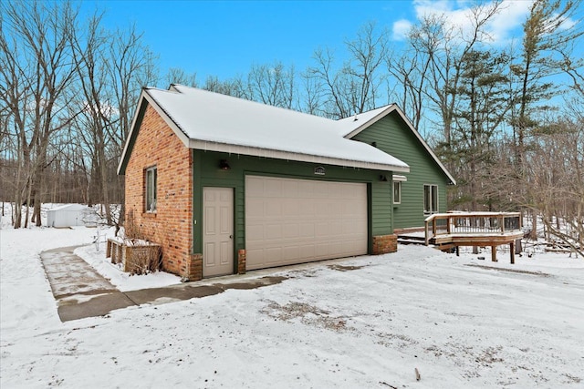 view of snowy exterior featuring a wooden deck and a garage