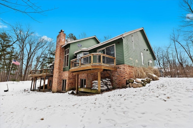 snow covered rear of property with a wooden deck