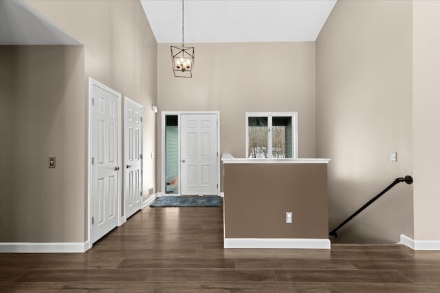 entryway featuring an inviting chandelier, dark wood-type flooring, and a high ceiling