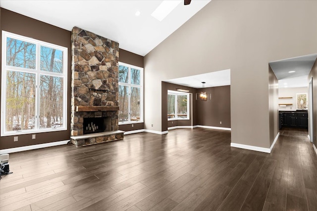 unfurnished living room with an inviting chandelier, a fireplace, dark hardwood / wood-style flooring, and high vaulted ceiling