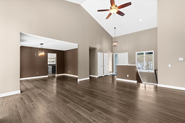 unfurnished living room with dark hardwood / wood-style flooring, ceiling fan with notable chandelier, and high vaulted ceiling