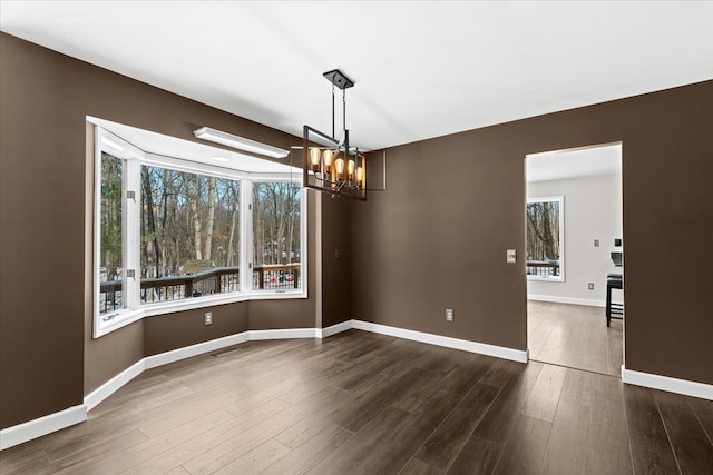 unfurnished dining area with an inviting chandelier and dark hardwood / wood-style floors