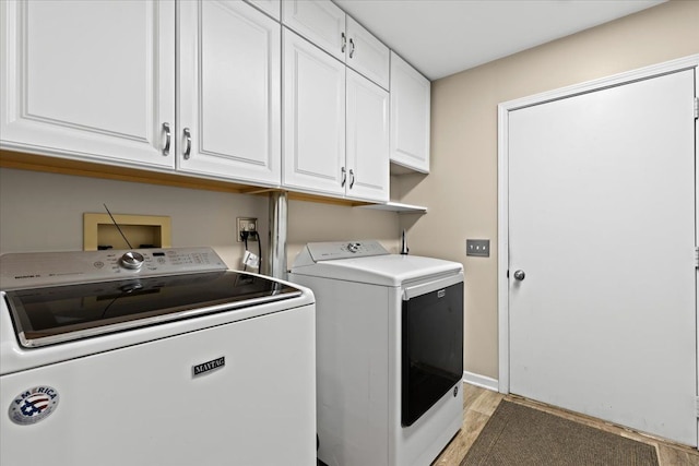 washroom with separate washer and dryer, light hardwood / wood-style floors, and cabinets